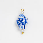 A small decorative bead or charm with a white base, blue hand-drawn style fish pattern, and gold-tone loop and bead accents, shown on a plain white background.