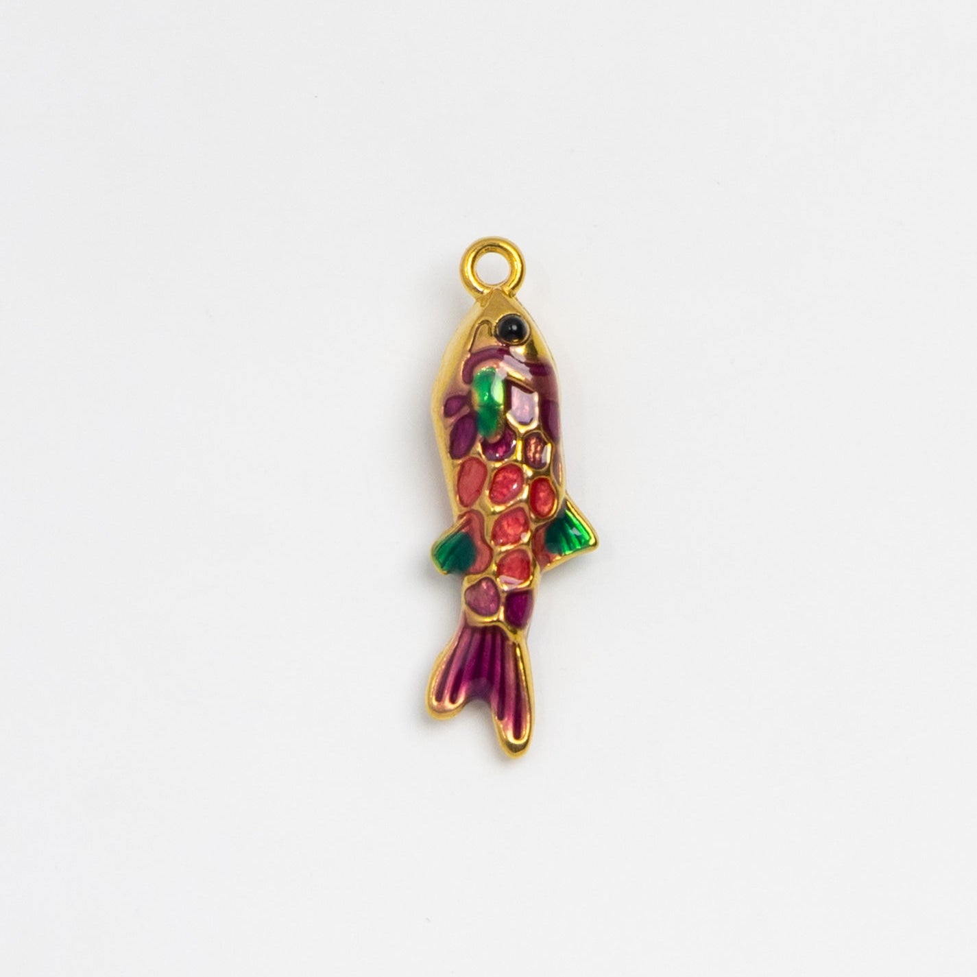 A small gold fish-shaped charm with colorful enamel detailing in red, green, and purple, shown on a plain white background.